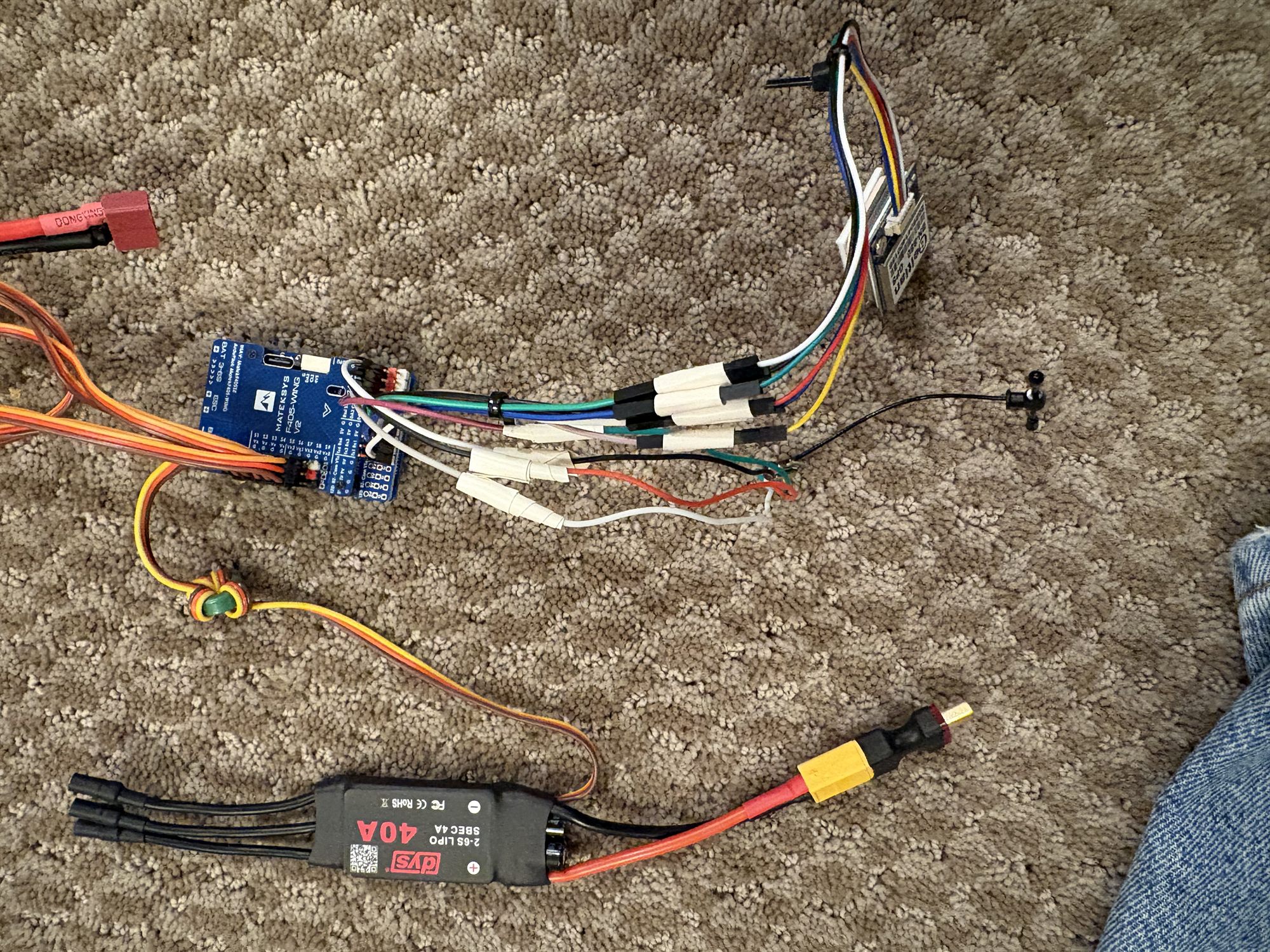The avionics laid out before installation: the Matek F405-Wing V2 flight controller, a GPS module, a 40 A ESC, and the servo and power harness.