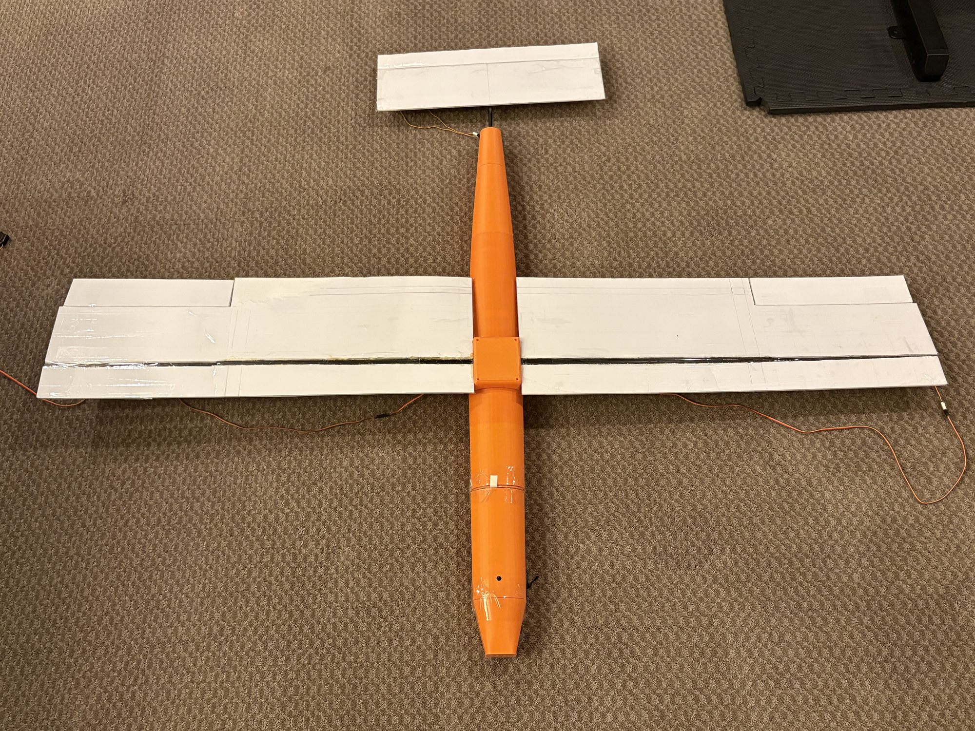 The assembled aircraft from above: printed fuselage, foam-board wings with the spar tube running spanwise, and the tail surface.