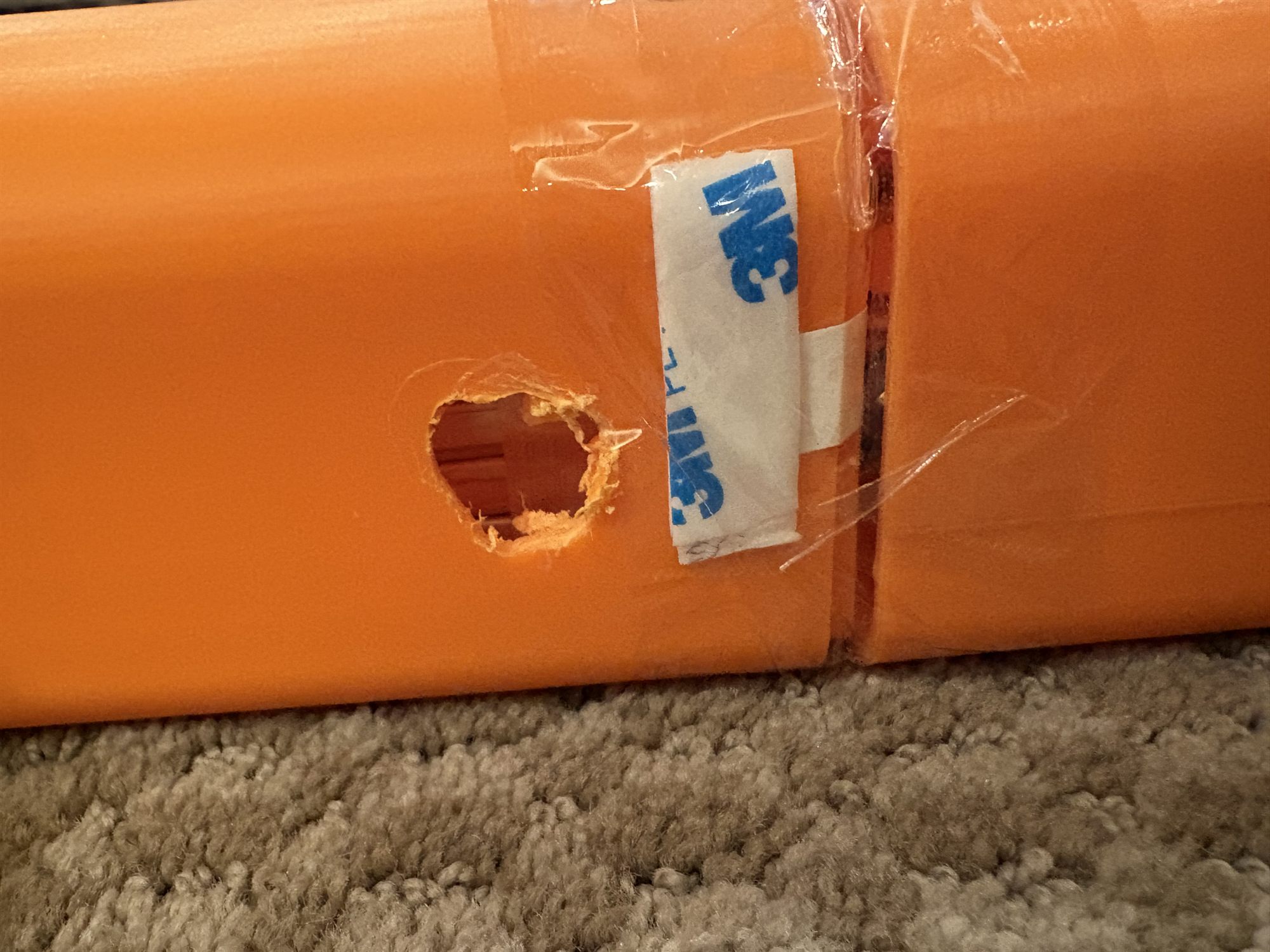 A ragged hole cut through the printed fuselage skin next to a taped section joint, the only way in once the airframe was glued shut.